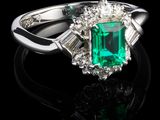 un gros plan d'une bague sertie d'une émeraude et de diamants sur une surface noire