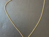 a gold necklace with a blue and yellow pendant on it