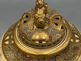 a gold and white bowl with a lid on a table