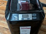 une petite machine à laver noire posée sur une table en bois