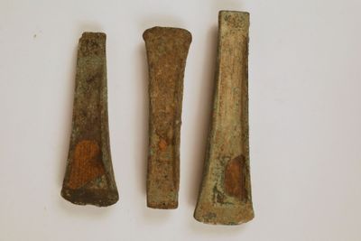 trois morceaux de métal sont posés les uns à côté des autres sur une surface blanche