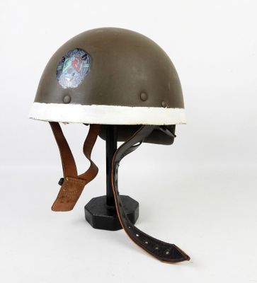 un vieux casque orné d'un autocollant, posé sur un support
