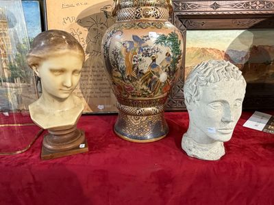 trois vases et un buste posés sur une table rouge