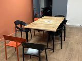 tables and chairs in a room with orange walls and wood flooring
