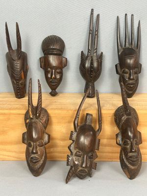 six masques africains en bois fixés sur un mur en bois