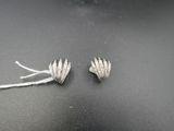 paire de boucles d'oreilles en forme de fleurs plaquées argent sur un fond noir