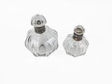 pair of clear glass salt and pepper shakers on a white surface