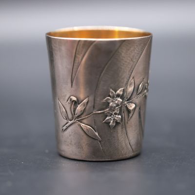 a silver cup with a flower design on it