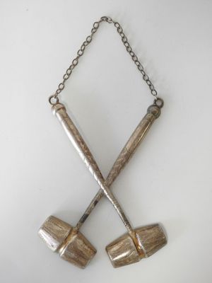 two wooden mallets hanging from a chain on a white wall