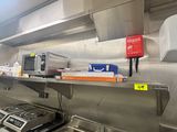 une cuisine équipée d'une cuisinière, d'un micro-ondes et d'autres objets rangés sur les étagères