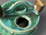 a green teapot with a bamboo stick sticking out of it