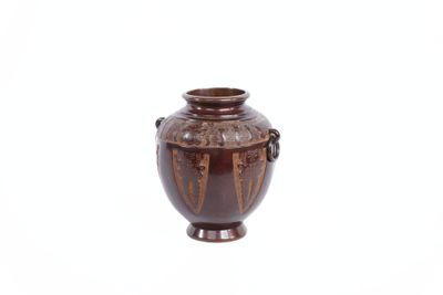 un vase brun posé sur une surface blanche