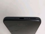 the back of a black cell phone sitting on top of a white table