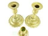 two gold candlesticks sitting next to each other on a white surface