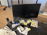 a computer monitor sitting on top of a table next to a cell phone