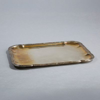 une image représentant un plateau en argent muni d'une poignée, posé sur une table