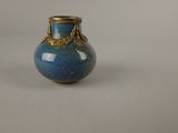a small blue vase with a gold decoration on it