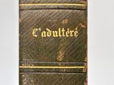 an old book with gold writing on it sitting on a white surface