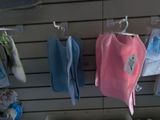 many baby clothes hanging on a rack in a store