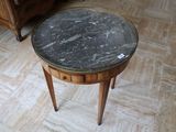 une table avec un plateau en marbre posée sur un piètement en bois, dans une pièce