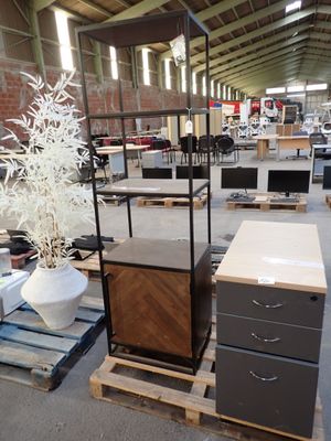 a lot of furniture in a warehouse with a plant in the middle of the room