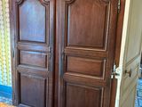 a wooden armoire in the corner of a room with a table and chairs