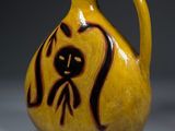 un vase jaune orné d'un motif noir et marron