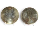une paire de plaques en laiton ancien posées sur des supports, sur un fond blanc