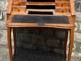 an old wooden desk with a black top and a stone wall in the background
