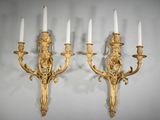 pair of gilded wall sconces with candles on each of them