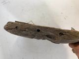 someone is holding a piece of drift wood with a hole in it