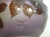 a purple vase with leaves on it on a table