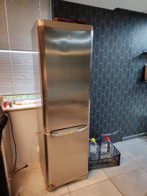 un réfrigérateur en acier inoxydable dans une cuisine aux murs carrelés de bleu
