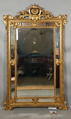 a large mirror with a gold frame on the wall