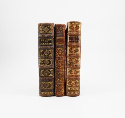 trois vieux livres posés l'un sur l'autre sur une surface blanche
