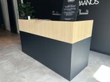 the front desk of an office with a black wall and a wooden counter