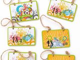 quatre étiquettes aux motifs variés sont suspendues à une ficelle sur une surface blanche