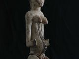 une statue en bois représentant un homme tenant un oiseau, sur fond noir