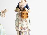two figurines of a woman and a bird on a table