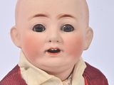 a baby doll with a red vest and a white shirt