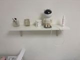 a white shelf with a doll on it next to a toilet