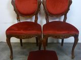 trois chaises rouges et un repose-pieds devant un mur blanc