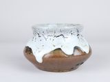 a small brown and white vase with a white glaze on it