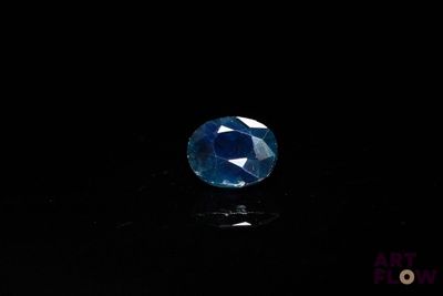 a close up of a blue sapphire stone on a black surface