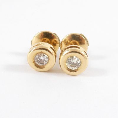 une paire de boucles d'oreilles à clous en or jaune et diamants sur fond blanc