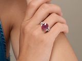 the woman is wearing a ring with a ruby stone on it
