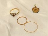 three gold rings and a ring with a diamond on top of a white cloth
