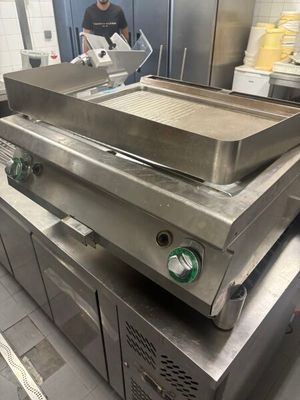 un homme debout dans une cuisine, en train de préparer un repas sur un barbecue