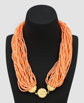 a necklace with orange beads and a gold clasp on a mannequin