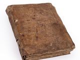 an old book is sitting on a white surface with a white background